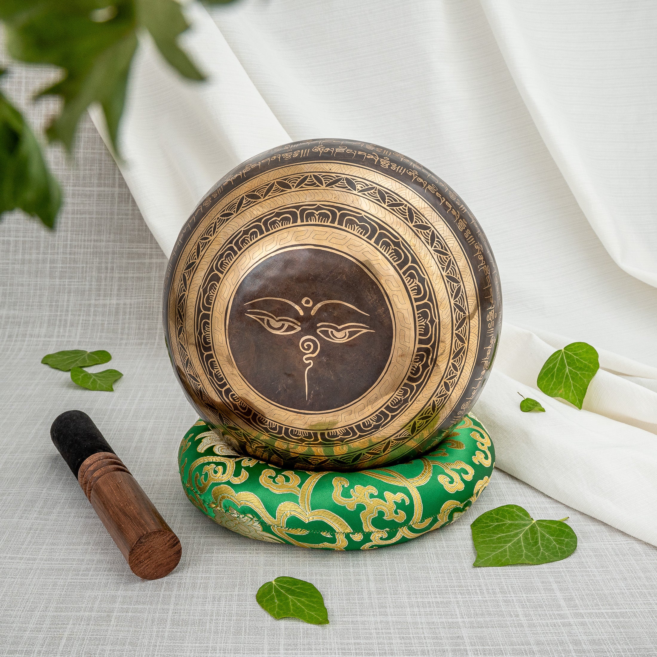 Bottom of crossed vajra singing bowl on green cushion