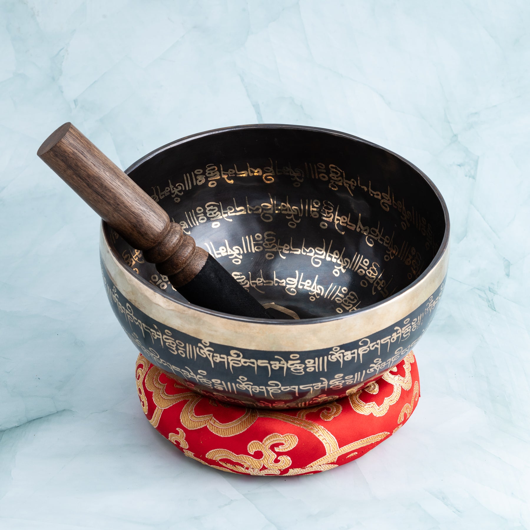 Singing bowl with striker and red cushion