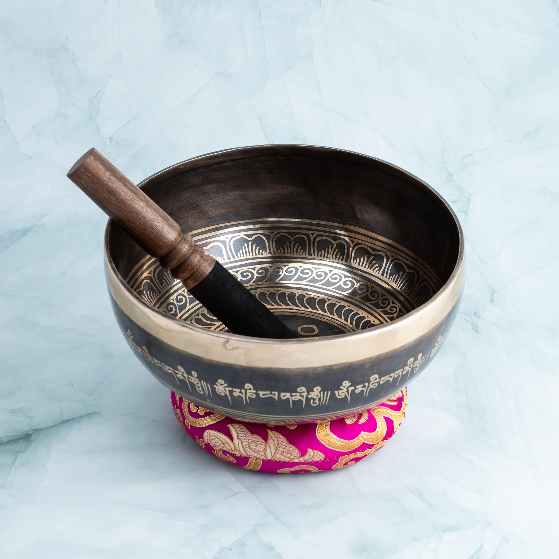 Singing bowl with wooden mallet and pink cushon