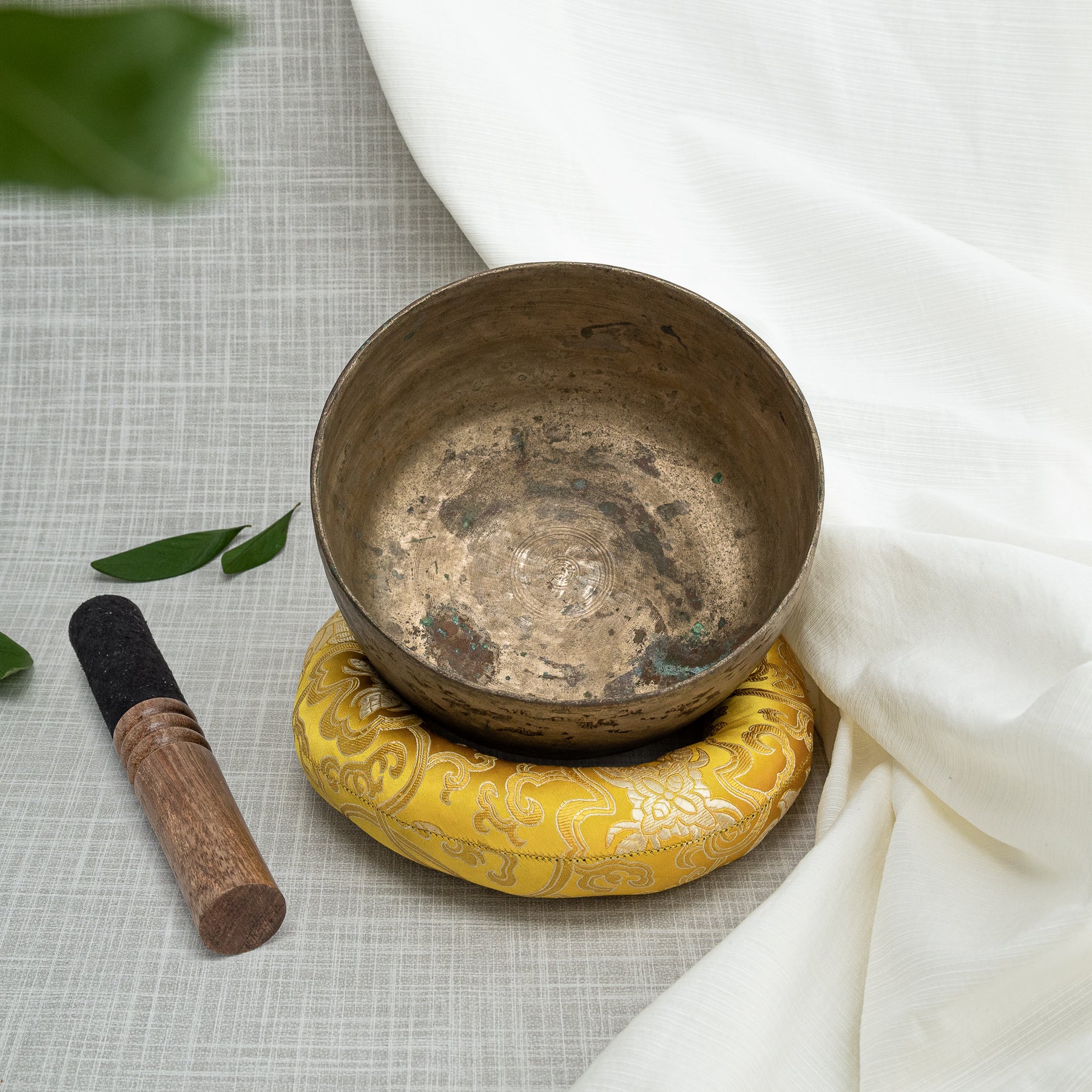 Antique singing bowl with mallet and cushion